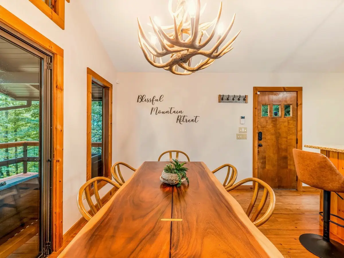 Long wood dining table under an antler chandelier